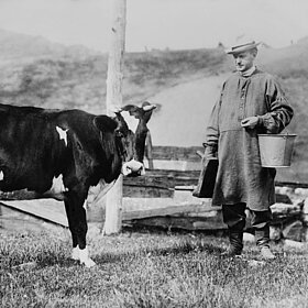Schwarz-Weiß-Foto von einem Mann und einer Kuh