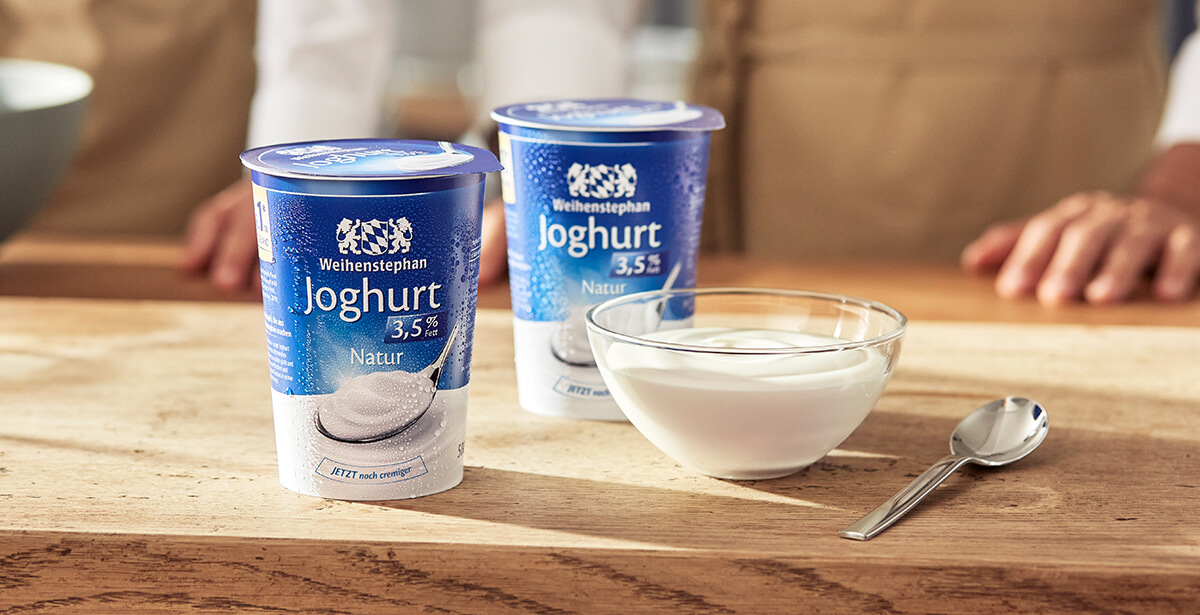 Zwei große Weihenstephan Joghurt-Becher neben einem Glasschälchen voller Joghurt